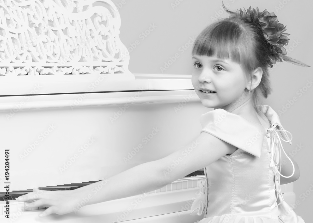 A girl is posing near a white grand piano. A girl is posing near a white grand piano.
