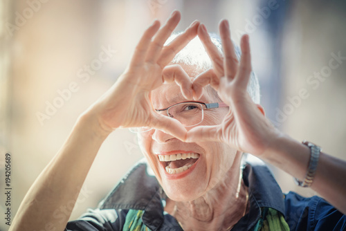Cute senior old woman making a heart shape with her hands and fingers photo