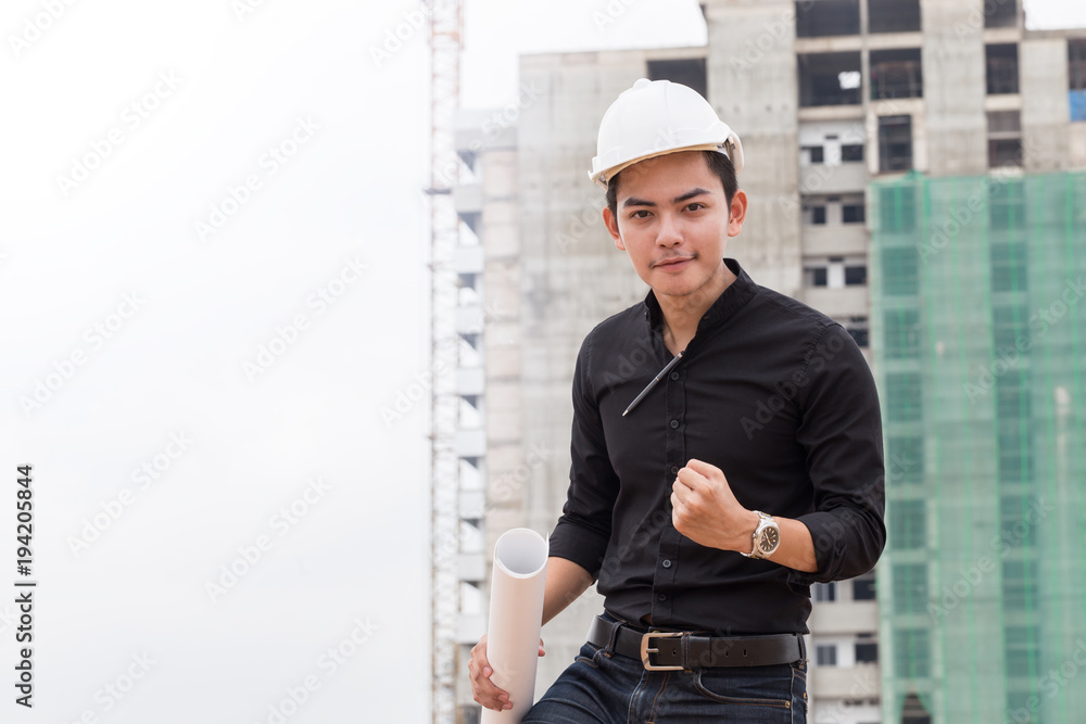 Engineer with white helmet holding blueprint and celebrating in construction site Engineer with white helmet holding blueprint and celebrating in construction site