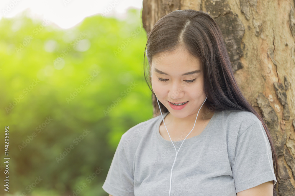 Beautiful Asian young woman relaxing with music in park Beautiful Asian young woman relaxing with music in park