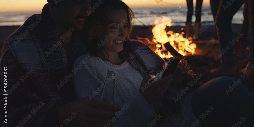 Couple enjoying bonfire with friends on beach Couple enjoying bonfire with friends on beach
