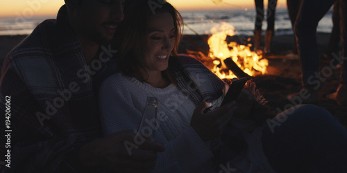 Couple enjoying bonfire with friends on beach