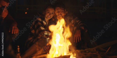 Couple enjoying with friends at night on the beach