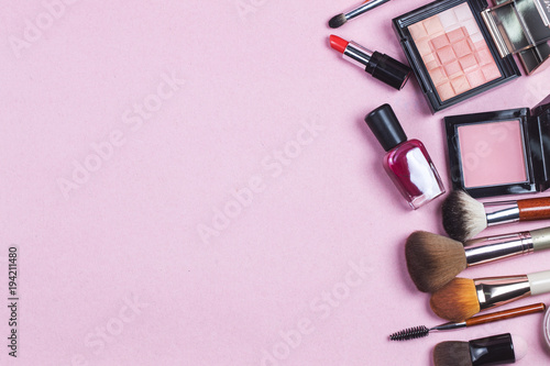 Fototapeta Naklejka Na Ścianę i Meble -  A pink leather make up bag with cosmetic beauty products spilling out on to a pastel background