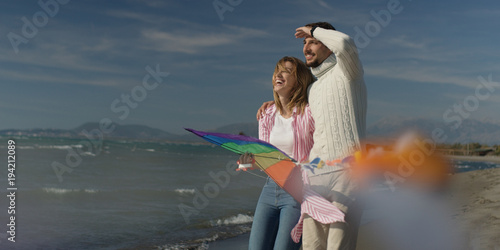 Happy couple having fun with kite on beach