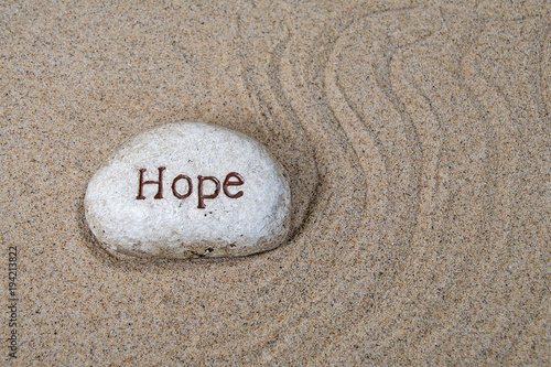 hope text engraved on a rock in beach sand with swirl design