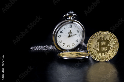 Single golden bitcoin and pocket watch on black background