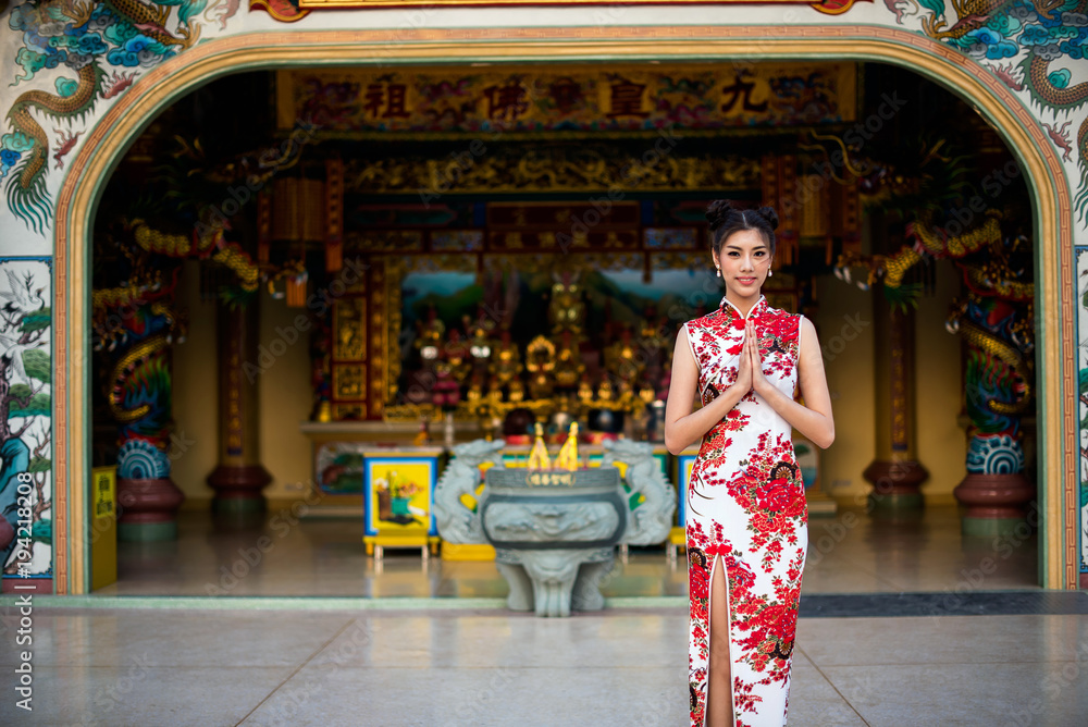 Fototapeta premium Asian woman wearing chinese dress, smile in chinese new year, Chinese woman dress traditional cheongsam at Chinese Temple.