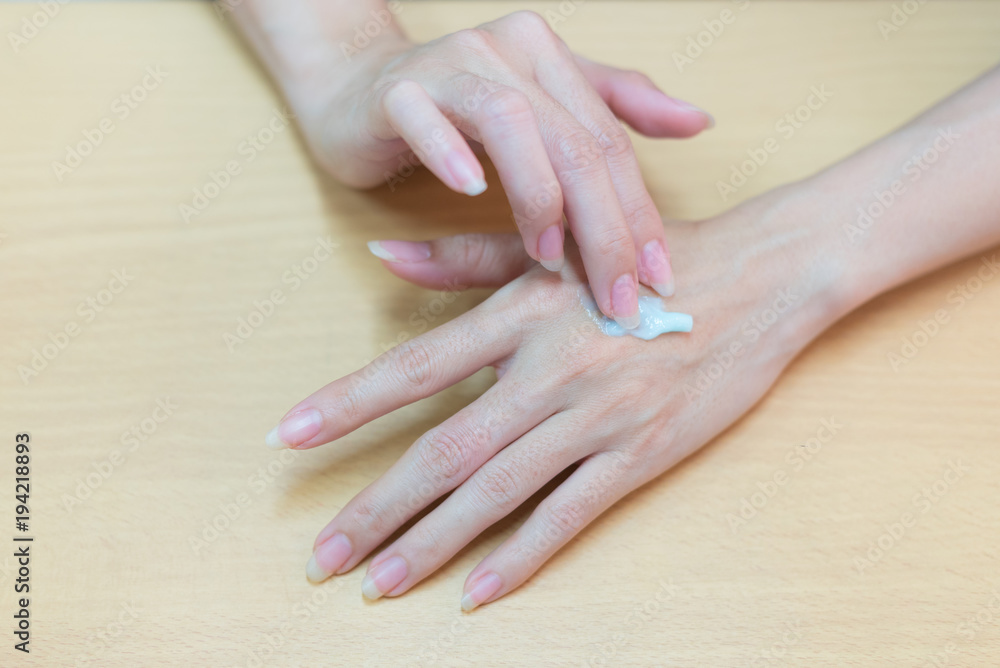 Naklejka premium Close-up for hard beautiful woman applying on hand cosmetic cream.