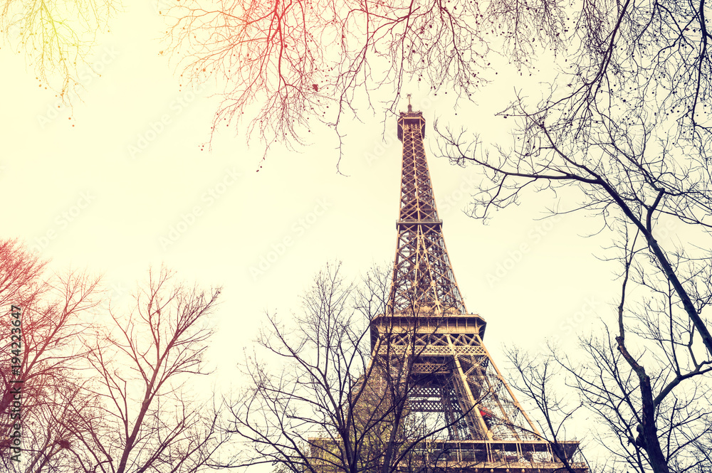 Eiffel Tower view through the trees in Paris, France. Vintage filter, retro effect