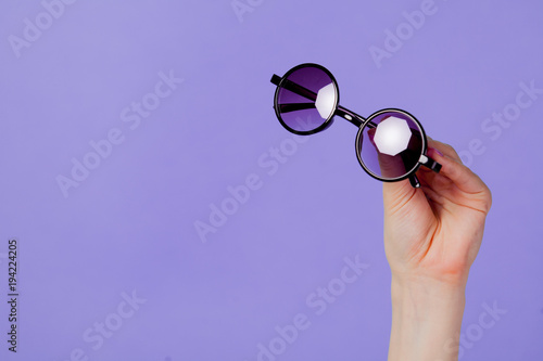 Female hand holding round sunglasses