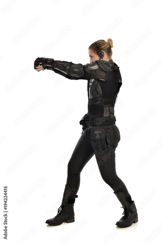 full length portrait of female soldier wearing black tactical armour with arms raised, isolated on white studio background. full length portrait of female soldier wearing black tactical armour with arms raised, isolated on white studio background.