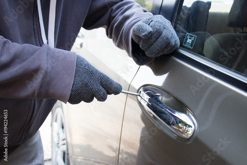 Foto Male thief stealing bag through the window of car.