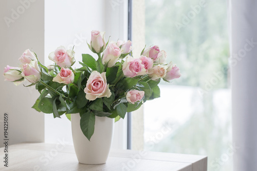 pink roses in vase on background window