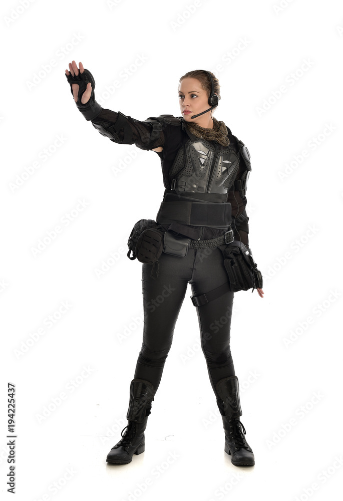 Fototapeta premium full length portrait of female soldier wearing black tactical armour with arms raised, isolated on white studio background.