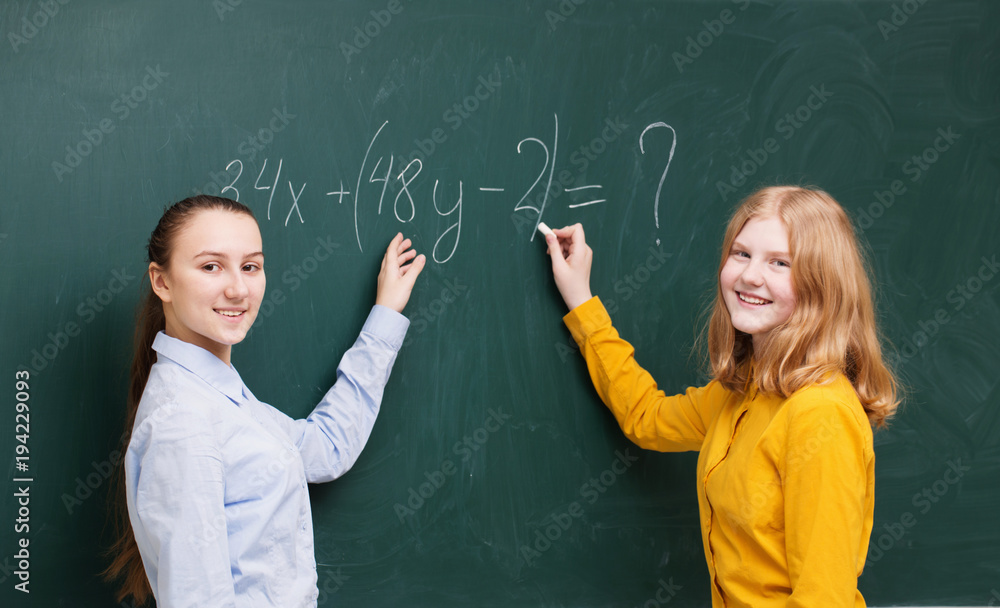 Two girls at the blackboard in a mathematics class