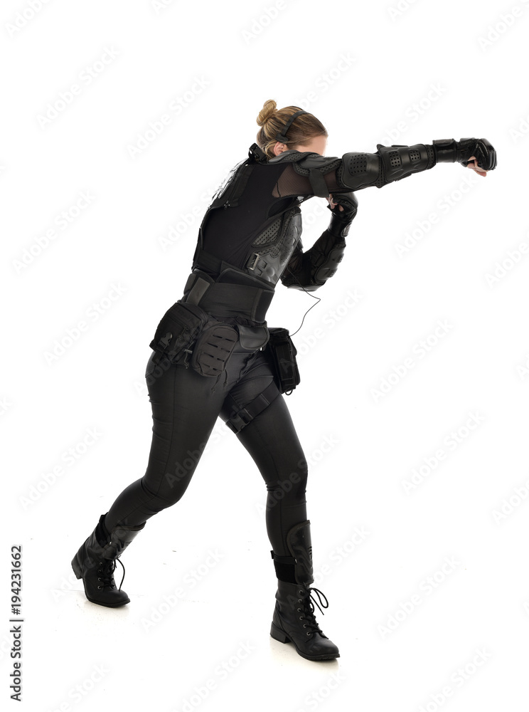 full length portrait of female soldier wearing black tactical armour with arms raised, isolated on white studio background. full length portrait of female soldier wearing black tactical armour with arms raised, isolated on white studio background.