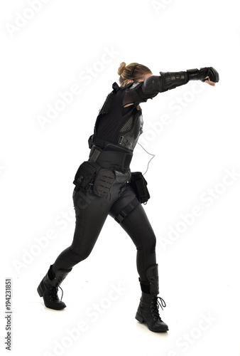 full length portrait of female  soldier wearing black  tactical armour with arms raised, isolated on white studio background. © faestock