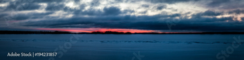 View of the winter lake under the snow and sunset