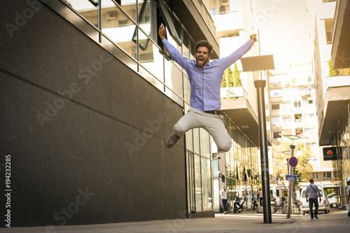 Successful business man jumping high. Man on city street.