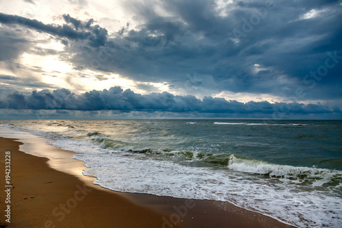 Dramatic sky on a morning seascape. Sunrise on a sandy beach.