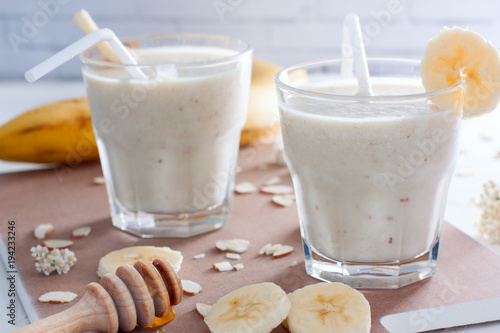 Two glass glasses with banana smoothie on a wooden board, horizontal