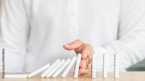 Stoping domino effect concept for business solution strategy and successful intervention with corporate person's hand blocking the collapse disruption photo