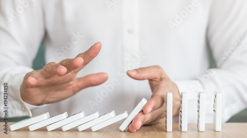 Stoping domino effect concept for business solution strategy, financial or investment protection and successful intervention with corporate person's hand blocking the collapse disruption photo