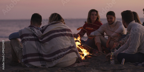 Group Of Young Friends Sitting By The Fire at beach