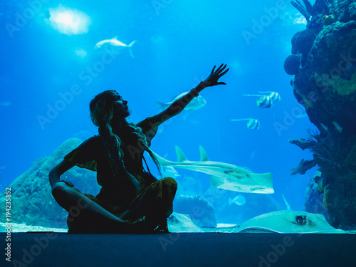 Girl watching fish through the glass in Oceanarium