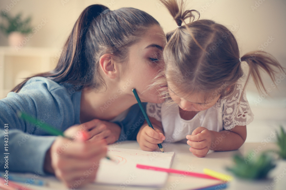 Mother and daughter at home. Mother teaching her daughter to drawing and writing. Mother and daughter at home. Mother teaching her daughter to drawing and writing.
