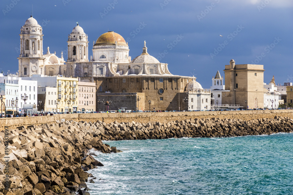 Views of Cádiz Cathedral (Catedral de Santa Cruz) from afar, with the coastline and the quay. Andalusia, Spain