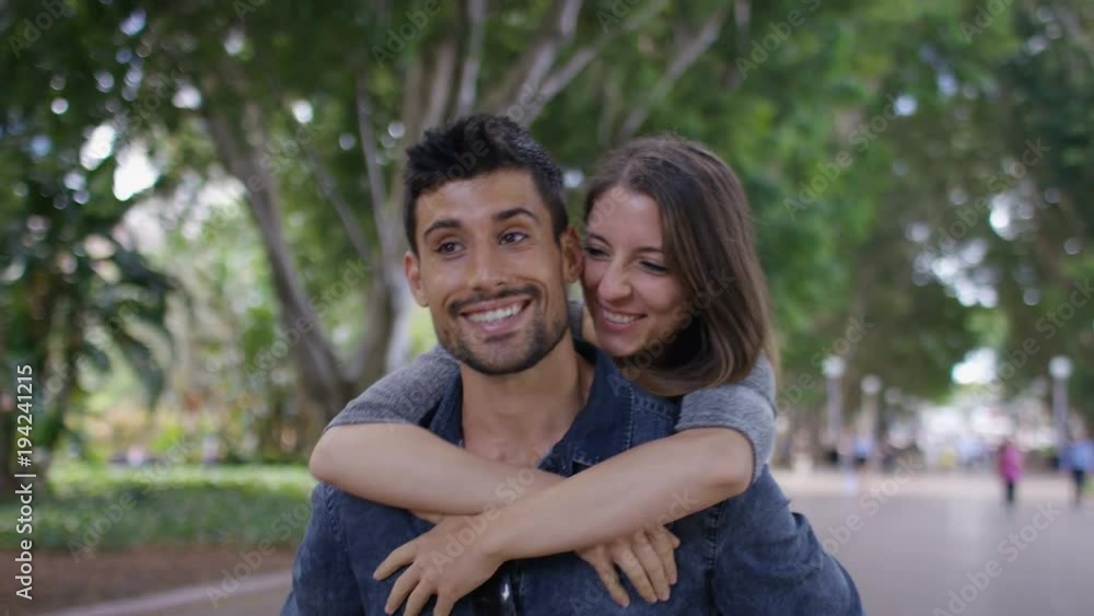 Happy young couple walking as the man carries the woman on his back, in slow motion Happy young couple walking as the man carries the woman on his back, in slow motion