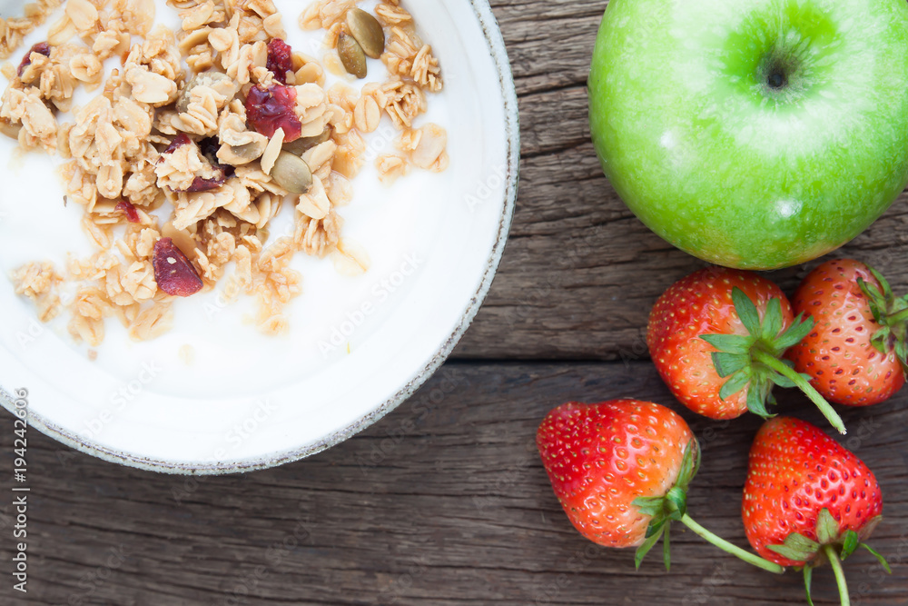 Yogurt with granola in a bowl, Green apple and strawberries on wooden table, Healthy and Diet concept Yogurt with granola in a bowl, Green apple and strawberries on wooden table, Healthy and Diet concept