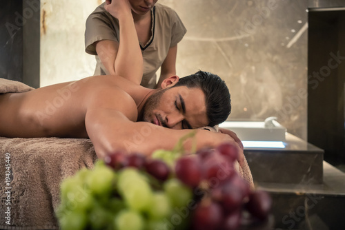 Photos Young man lying down during traditional acupressure procedure of Thai massage at