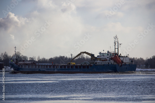 Logistics and transportation  Cargo ship with ports crane bridge coming in port and transportation industry winter suny day in Latvia baltic sea an river daugava.