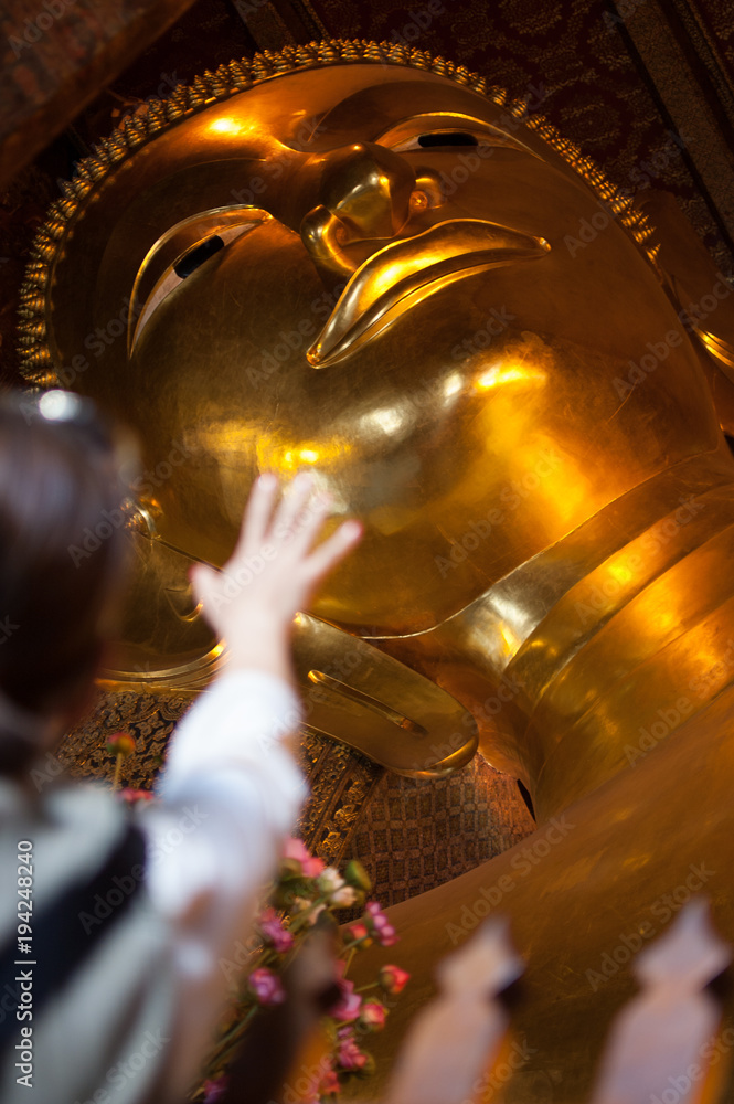 A Girl Trying to Reach the Big Golden Buddha in Thailand