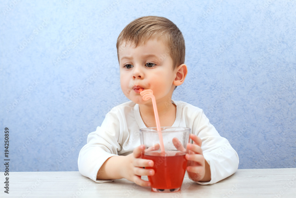 Cute little boy drinking juice on light blue background. Lovely kid drink grape juice. Cute little boy drinking juice on light blue background. Lovely kid drink grape juice.