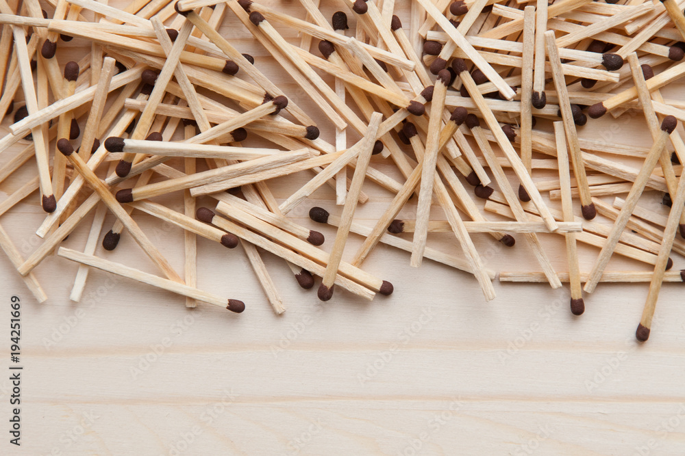 wooden unburned matches with black heads scattered against a light brown wood. empty space from below wooden unburned matches with black heads scattered against a light brown wood. empty space from below