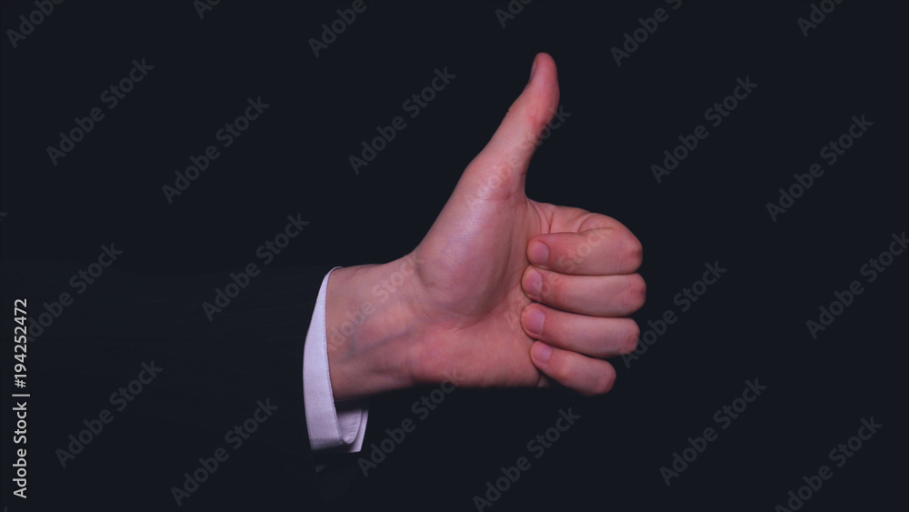Businessman in suit, thumb up (like), black background. Businessman in suit, thumb up (like), black background.