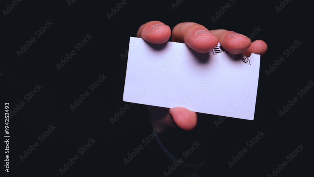 Businessman holding a business card, black background. Businessman holding a business card, black background.