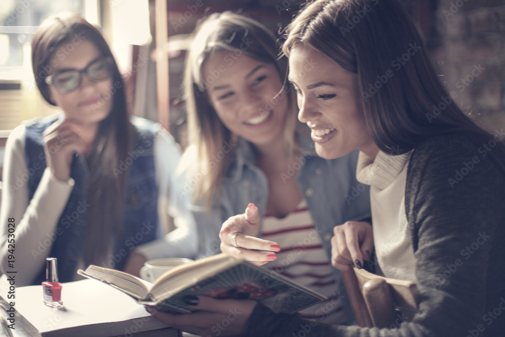 Three young students sitting together and reading book. Focus on foreground . Three young students sitting together and reading book. Focus on foreground .