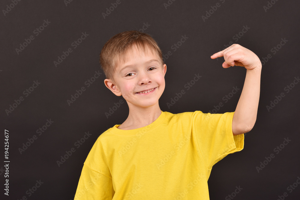Cheerful boy on a black background. Happy childhood. A child in a yellow T-shirt. Children on a dark background. Cheerful boy on a black background. Happy childhood. A child in a yellow T-shirt. Children on a dark background.