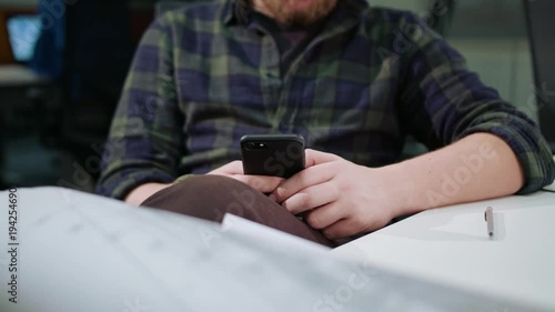 A young blonde man using a phone indoors. Close-up shot. Soft focus.