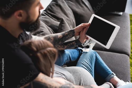 pregnant girlfriend looking at tablet with boyfriend at home