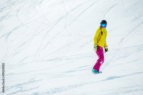 Image of woman wearing helmet in sports clothes snowboarding