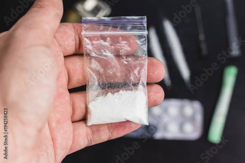 Man hand holds plastic packet or bag with cocaine or another drugs, drug abuse and danger addiction concept, selective focus