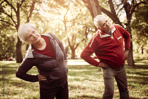 Active seniors couple in sports clothing working stretching and exercise in park. © Mladen