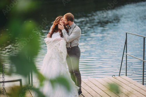 stylish bride and groom posing on the background of the river photo