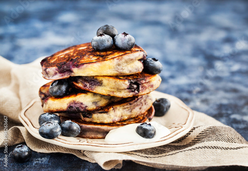 Stack of freshly prepared blueberry ricotta pancakes with fresh berries, yogurt and honey